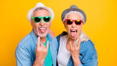 excited elders with sunglasses and rock on hands