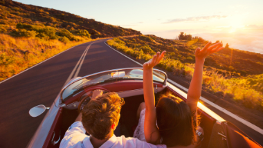 people in car arms up on a roadtrip
